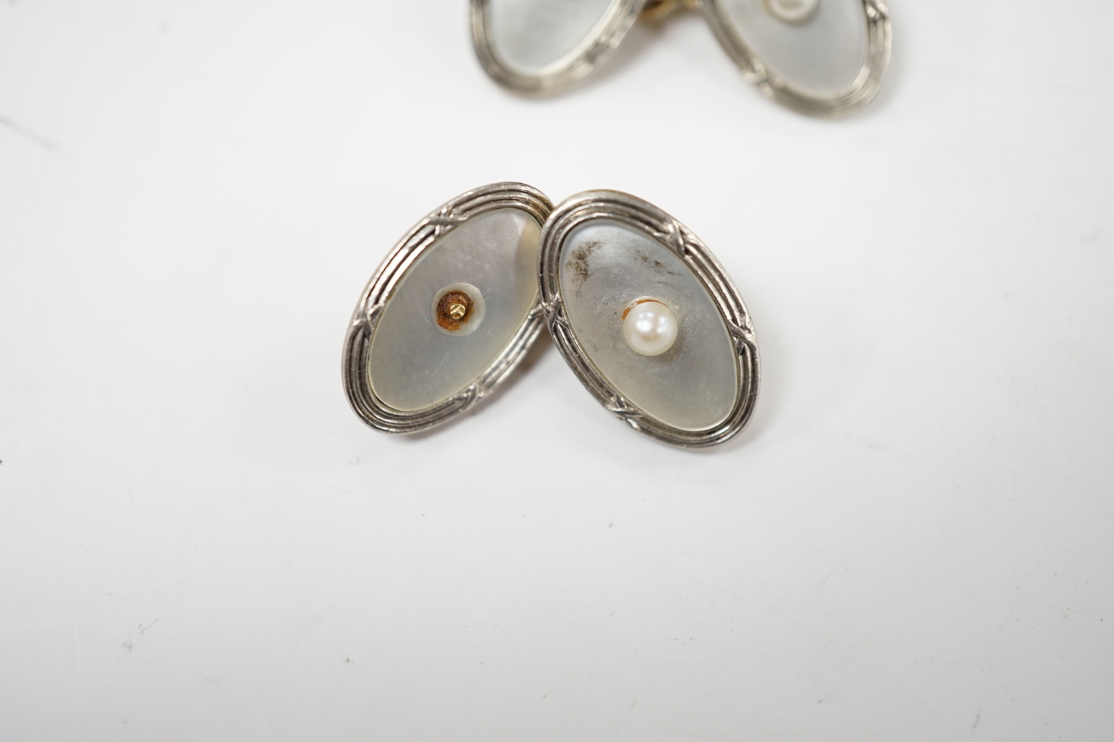 A pair of Edwardian 15ct, mother of pearl and seed pearl set oval cufflinks, 17mm, gross weight 7.3 grams.